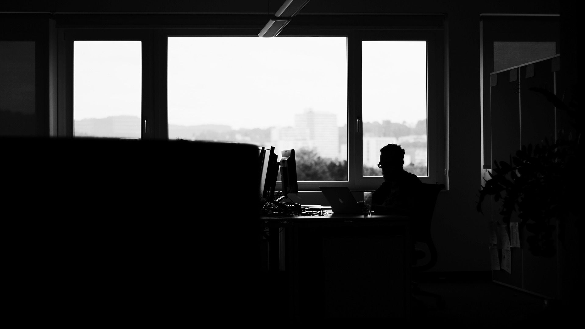 薄暗いオフィスにて1人で仕事をする男性