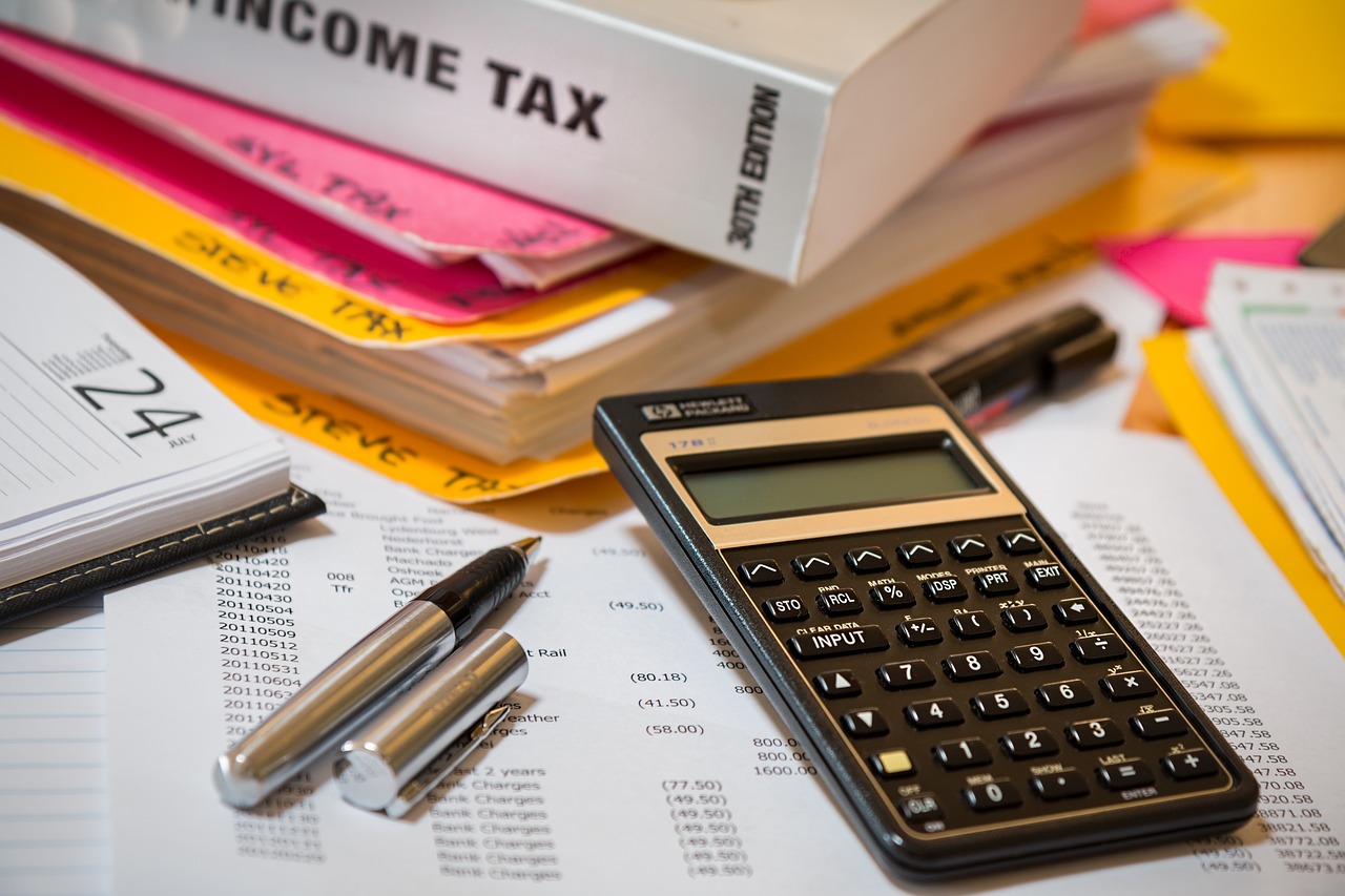 税務の実務書、電卓、経理資料、ペン